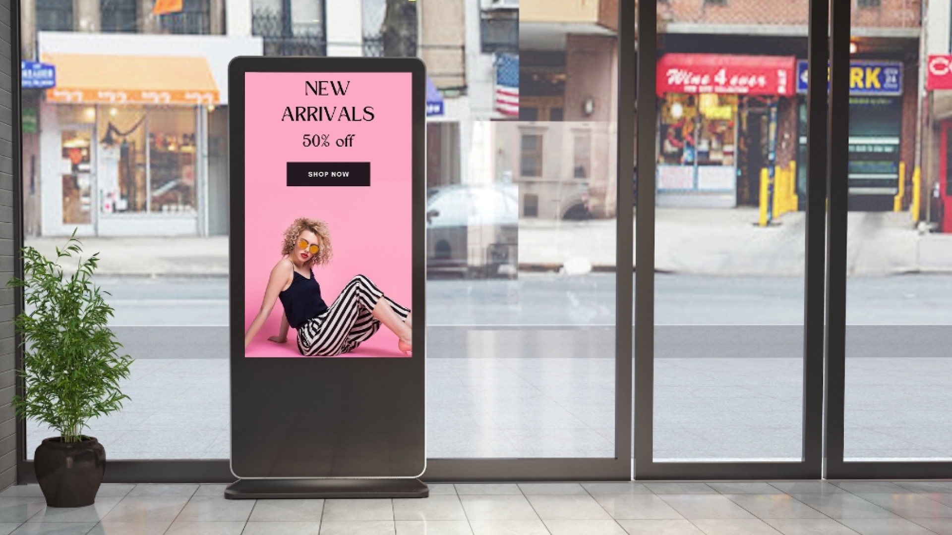 A digital signage display in a store promoting new arrivals with 50% off against a pink background.