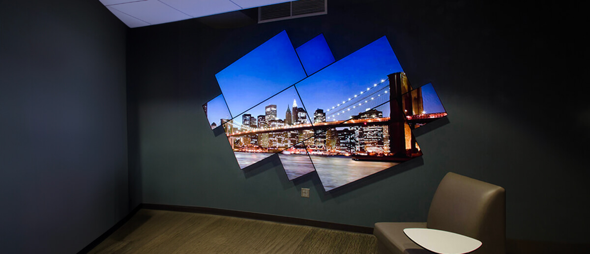 An artistic video wall with asymmetrically arranged screens displaying a vibrant city skyline at night.