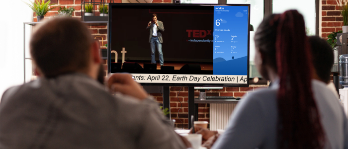 A group of school teachers stare at a digital screen inside the staff room as they watch a TEDX lecture on mentorship