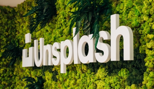 The name 'Unsplash' is embedded in a green living wall signage with thick moss & fern covering